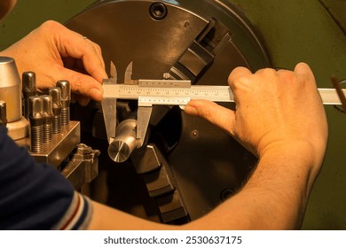 The machine operator measuring dimension of metal shaft parts by Vernier caliper on lathe machine. The quality control on turning machine.  - Powered by Shutterstock