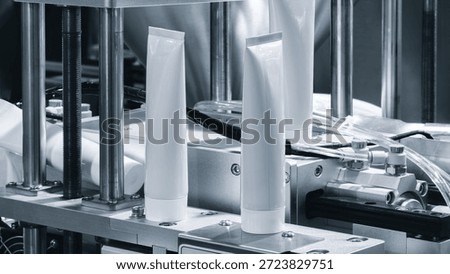 A machine for producing white plastic tubes and packaging for medicines, cosmetics, or household chemicals at a pharmaceutical cosmetics factory. Industrial concept background