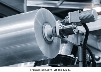 A machine with a roll of polyethylene plastic wrapping film on it. The machine is in a factory. industrial food packaging concept background