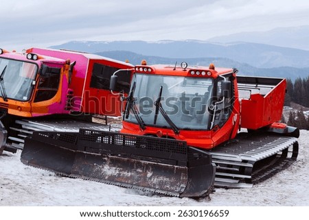 Machine for skiing slope preparations at background of mountains. Snowplow machine at snowy ski resort.