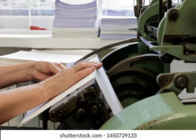 Machine for stitching book pages with threads in typography. Machine for sewing books and notebooks with threads. Women at work.