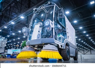 Machine for sweeping roads. Street cleaning vehicle. Demonstration of cleaning equipment at the exhibition. Machine with yellow cleaning brushes. Municipal utilities.