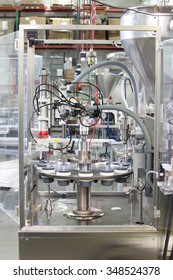 Machinery in a cosmetics factory, filling small vials with liquid.