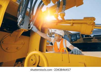 Machinery tractor mechanic checks hydraulic hose system equipment on excavator.