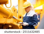 Machinery tractor mechanic with tablet computer checks hydraulic piston hose system equipment on excavator. Industrial service of mining truck.