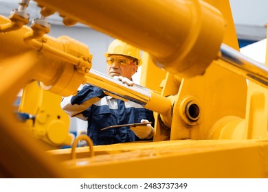 Machinery tractor mechanic with tablet computer checks hydraulic piston hose system equipment on excavator. - Powered by Shutterstock