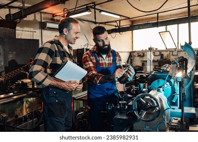 A machinist and an engineer measuring a newly-made metal part in a factory, at a metallurgy machine (lathe). The engineer is holding a clipboard, the machinist is holding a bearing and a caliper. - Powered by Shutterstock