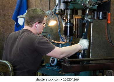 Machinist Taps Threads Into Steel Using A Drill Press In Production Work In A Metal Shop.