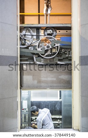 Machinist worker technicians at work adjusting lift with spanners in elevator hoist way