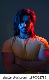 Macho man. Masculine power. Cyberpunk fashion portrait. Neon light people. Confident guy yellow t-shirt crossing hands chest dark blue red vibrant color glow isolated deep ocean. - Shutterstock ID 1990322795