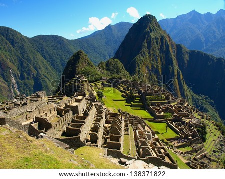 Machu Picchu in Peru - lost city of Incan Empire is UNESCO heritage. Sunny summer day with blue sky and clouds.