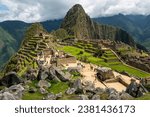 Machu Picchu ruins with tourists with dramatic clouds, Machu Picchu historical Sanctuary, Cusco, Peru.
