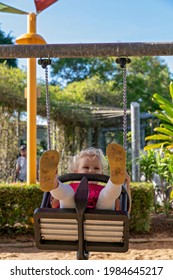 Mackay, Queensland, Australia - June 2021: A young female child enjoying a swing in the playground