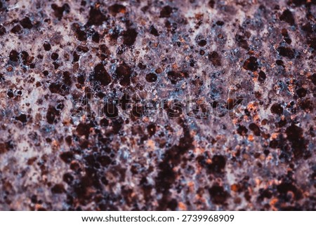 Macro abstract of a weathered metallic surface featuring deep pitting, oxidation, and a rich palette of purple, rust, and dark umber tones. The textured industrial decay creates a celestial or organic appearance, ideal for backgrounds, textures, and conceptual designs representing erosion, time, or cosmic phenomena.