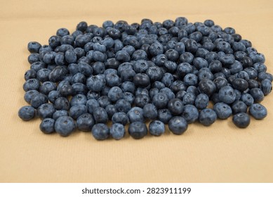 Macro background texture of fresh blue ripe blueberries scattered on a rustic cardboard surface. Organic summer harvest copy space banner.