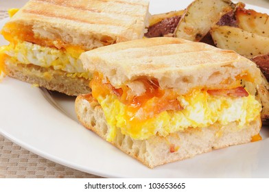 Macro Of A Bacon, Egg And Cheese Breakfast Panini With Fried Potato Wedges