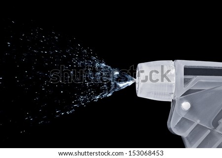 Macro of a bottle nozzle spraying water isolated on black background