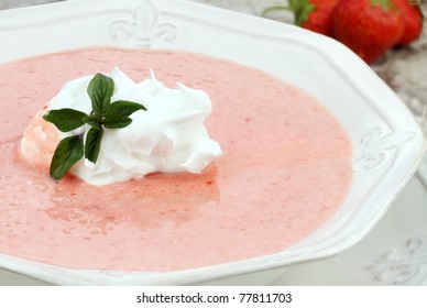 Macro Of A Bowl Of Chilled Strawberry Soup, Garnished With A Dollop Of Whipped Cream And A Fresh Sprig Of Chocolate Mint. Shallow Depth Of Field With Some Blur On Lower Portion Of Image.