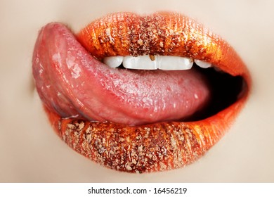 Macro Of Bright Orange Make-up On Lips With Tongue Licking Off Chocolate Powder