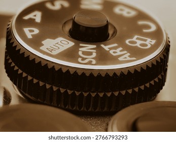 Macro close up of camera mode dial showing auto and scene settings with textured grip detail and warm lighting