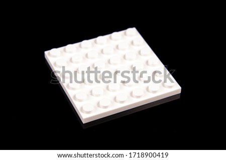 Macro close up of constructor toy white flat plastic brick isolated on the black reflective background