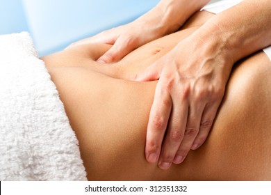 Macro close up of hands massaging female abdomen.Therapist applying pressure on belly.