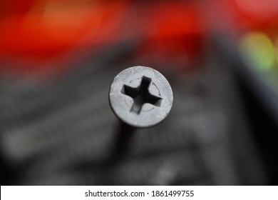 Macro close up of isolated grey crosshead screw head, blurred screws in tool box background (selective focus on upper part of screw head)