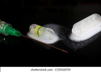 Macro Close Up Of Isolated Syringe With Injection Needle, Broken Glass Vial And White Liquid, Black Reflecting Background (selective Focus On Center)