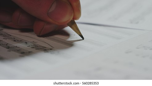 Macro Close Up Of Musician Or Composer Hand Writes A Song Or A Musical Work, Writing Notes With Pencil On The Pentagram. Concept: Conservatory, Music, Composer, Notes, Art, Life