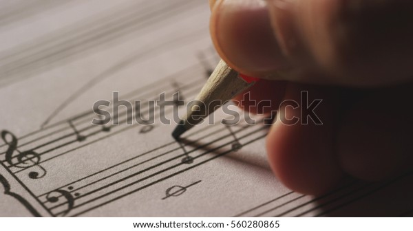 Macro\
close up of musician or composer hand writes a song or a musical\
work, writing notes with pencil on the pentagram. Concept:\
conservatory, music, composer, notes, art,\
life