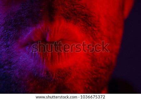 Macro close up on man with seductive facial expression pulled his lips to give a kiss. Portrait of flirty young man looking at camera.