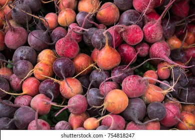 Macro close up on a pile of freshly harvested beet roots, in shades of orange and purple, making a background