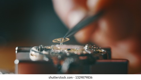 Macro close up of a professional watchmaker repairer working on a luxury mechanism watch gears engine in a workshop.  - Powered by Shutterstock