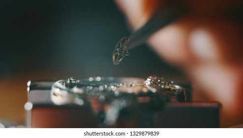 Macro close up of a professional watchmaker repairer working on a luxury mechanism watch gears engine in a workshop. 