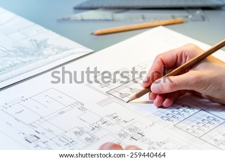 Macro close up of quantity surveyors hand reviewing technical drawing.