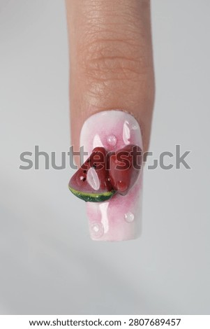Macro close up of single fingernail decorated with volumetric red watermelon pieces