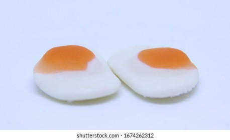 A macro close up view of poached egg shaped gummy jellies isolated on white.