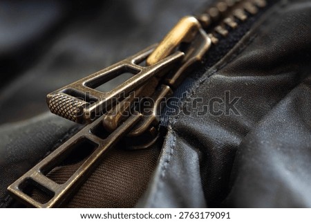 A macro closeup abstract image of a double zip. The metals zips fasten each side of a leather coat which is gnarled and wrinkled around the edge of the fastening. 