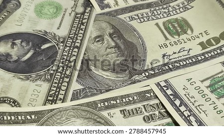 Macro close-up background of scattered US Dollar banknotes with a prominent focus on Benjamin Franklin's portrait on the 100 dollar bill. Concept of wealth, cash texture, and American currency.