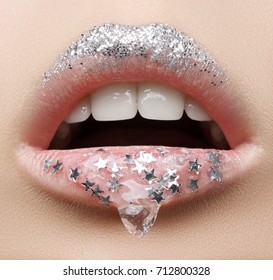 Macro and close-up creative make-up theme: beautiful female lips with a transparent gel on the lips and small silver stars and sparkles