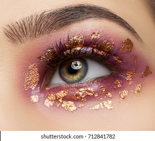 Macro and close-up creative make-up theme: beautiful female eyes with red shadows pigment and gold sparkles