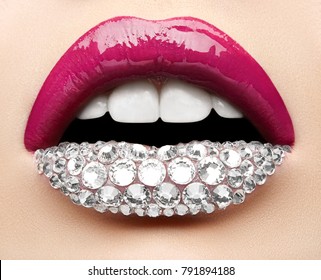 Macro and close-up creative make-up theme: beautiful female lips with pink lipstick, white diamonds and teeth, retouched photo