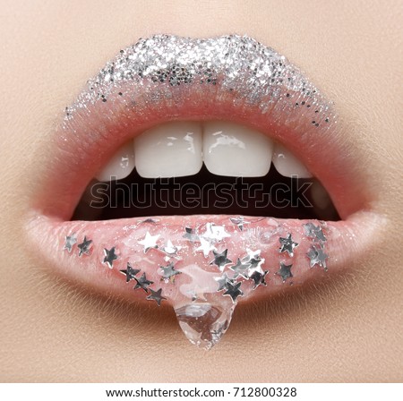 Macro and close-up creative make-up theme: beautiful female lips with a transparent gel on the lips and small silver stars and sparkles