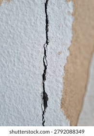 Macro Close-up of Deep Vertical Crack on Old White Stucco Concrete Wall with Peeling Paint
