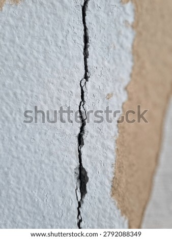 Macro Close-up of Deep Vertical Crack on Old White Stucco Concrete Wall with Peeling Paint