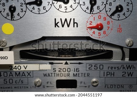Macro close-up of a domestic kWh electric meter and slow turning measuring dial. Concept for energy, utility bills, price rise, meter reading, inflation and electricity supplier.