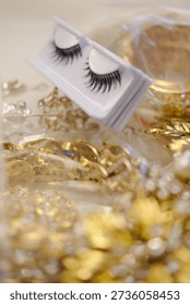 Macro close-up of false eyelashes in packaging with golden sparkling background. Ideal for bridal makeup, glam fashion, salon advertising and beauty branding.