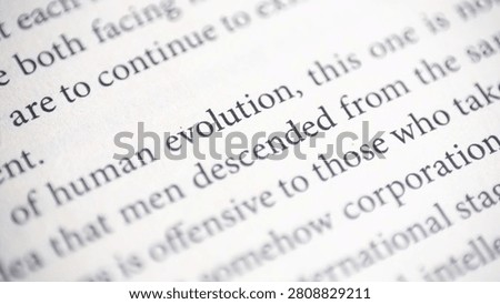 Macro close-up highlighting the printed word “evolution” on a book page with shallow depth of field. Educational concept related to science, biology, reading, and literature.