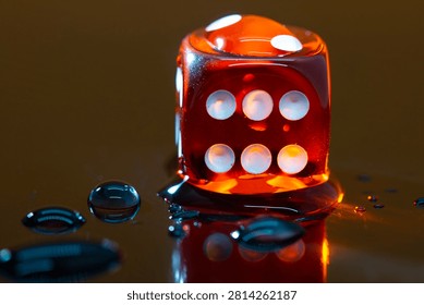 A macro closeup image of a single orange dice surrounded by water doplets. The translucent dice shows the number six on its side as light refracts and scatters on a shiny surface to the right.