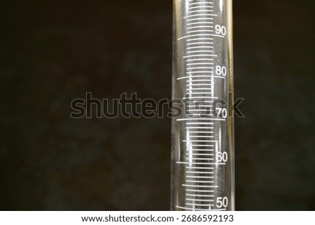 Macro close-up on the precise milliliter scale and graduations of an empty glass graduated cylinder, used for accurate liquid measurement in a chemistry laboratory, representing precision and scientif